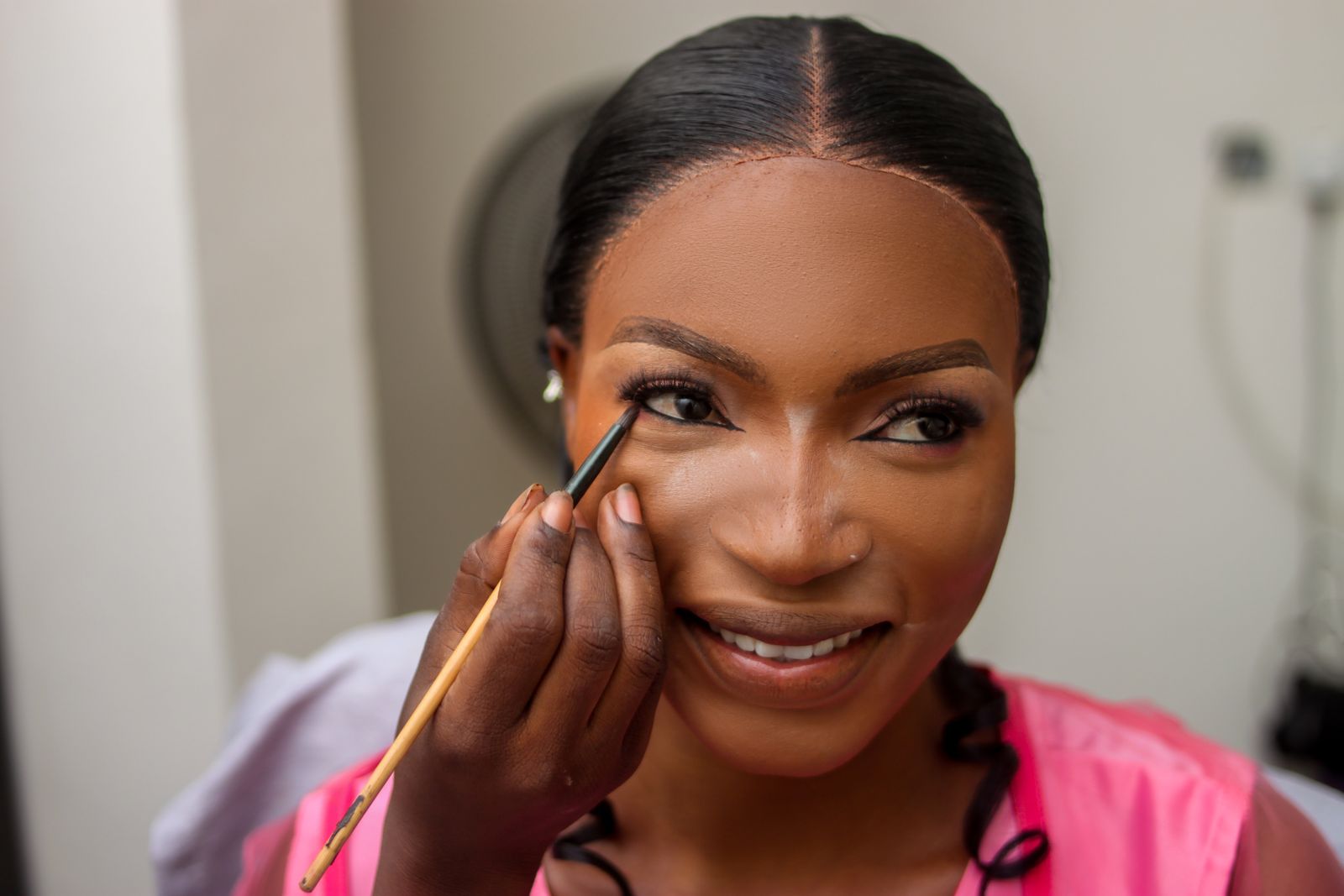 A wooden contouring roller worked along the thigh of a client with deep brown skin draped in cream towels