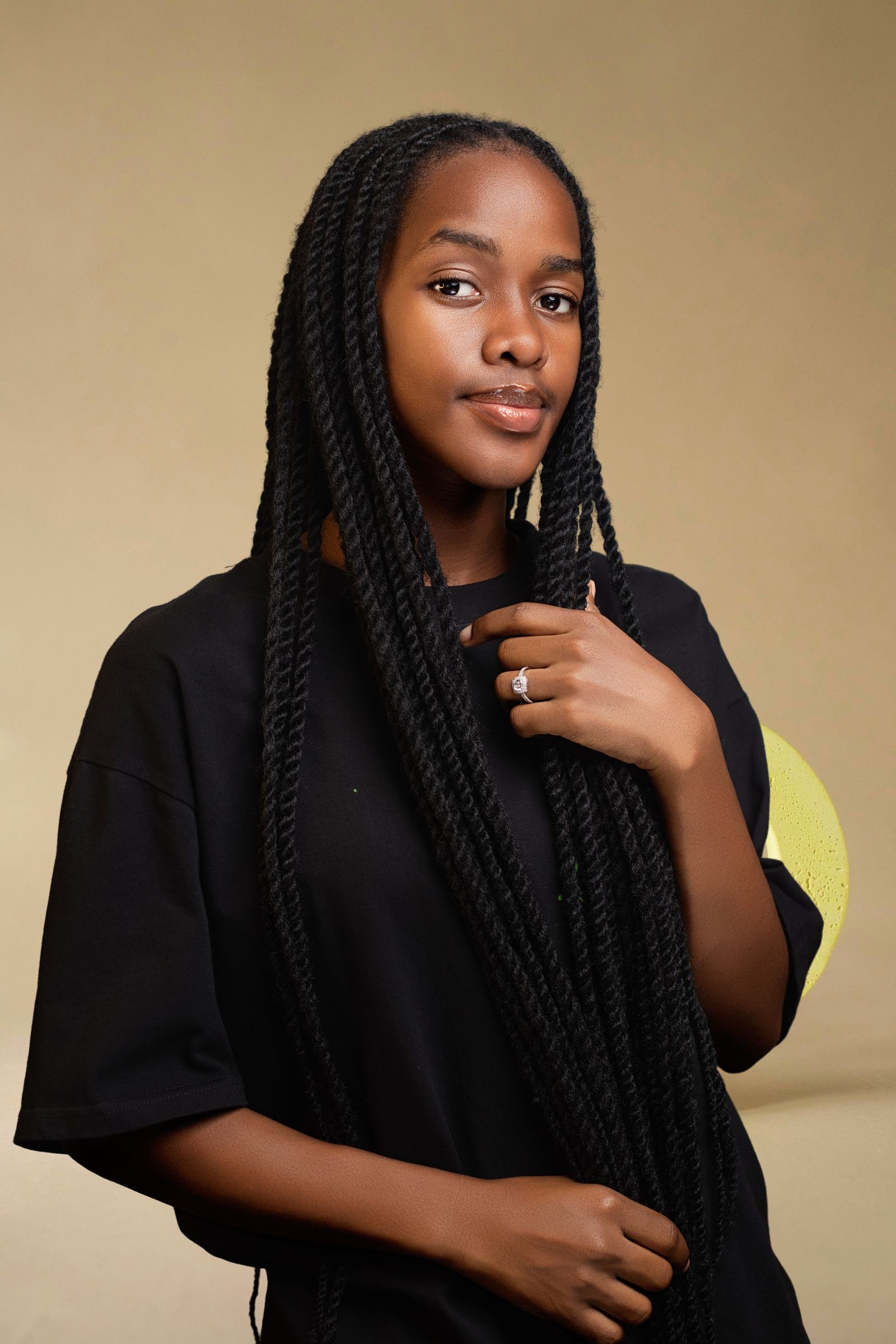 A woman with deep brown skin wearing long boho knotless braids with loose curled ends